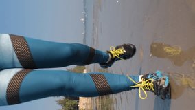 Vetical video. Close-up of young sporty woman running on a sandy beach, enjoying active summer vacation , slow motion