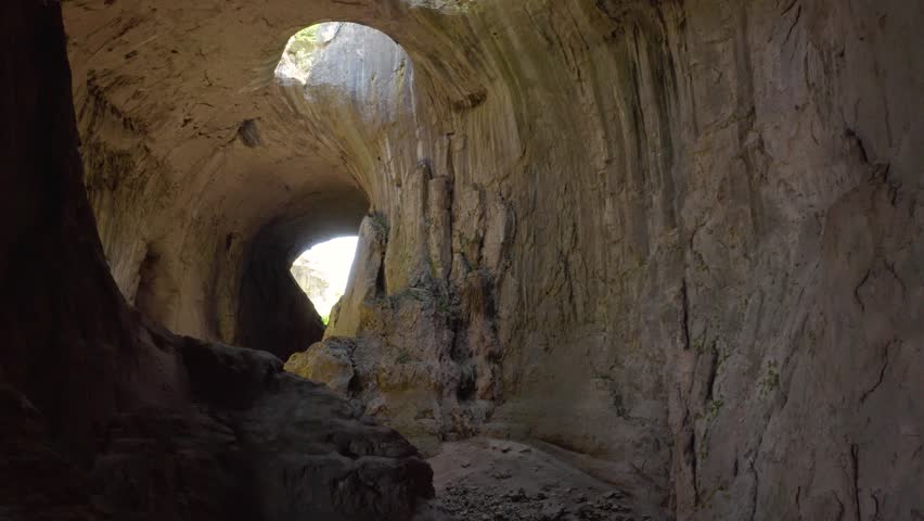 Follow through shot of the tunnels going to the chambers of Prohodna Cave, passing by limestone walls and stalagmites where holes known as God's Eyes can be seen in Karlukovo, in Bulgaria. Royalty-Free Stock Footage #3475525011