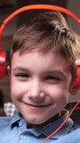 vertical video portrait of a little boy in orange headphones listening to music,