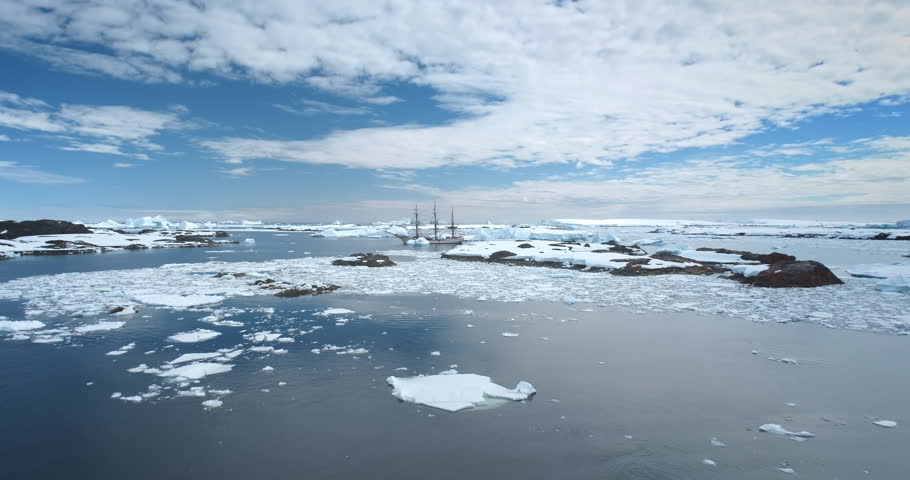 Travel to Antarctica, expedition on wooden yacht. Boat tour South Pole. Explore arctic wild nature in sunny day. Polar ocean, icebergs, blue sky. Winter holiday vacation background. Aerial drone shot