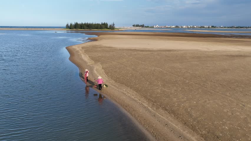 Two farmers with fishing net and baskets walking on the side of Tra Khuc river, Quang Ngai