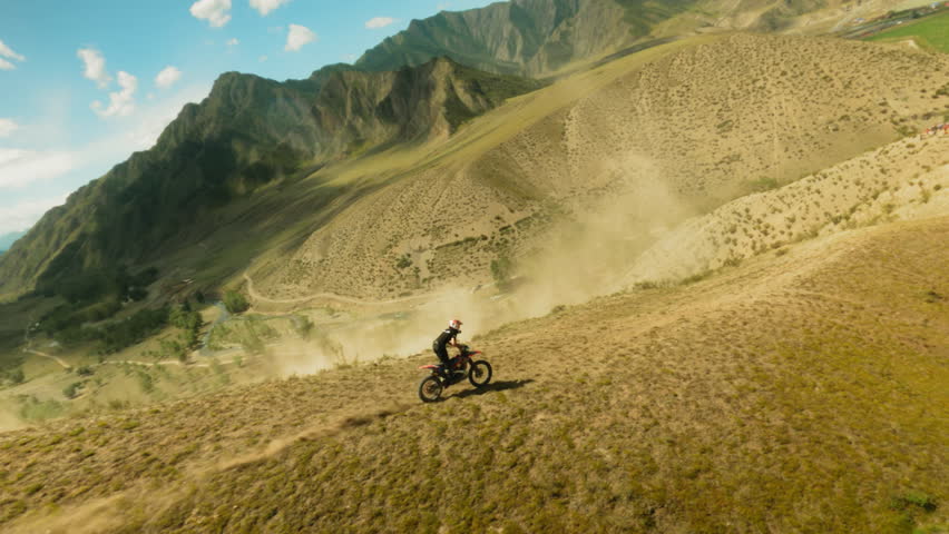 Extreme lover rides motorbike along hill ridge fpv drone. Motorcyclist on vehicle competes for victory in offroad racing at highland. Extreme hobby