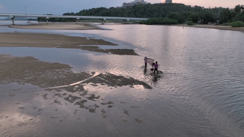Two farmers with fishing net and baskets walking on the side of Tra Khuc river, Quang Ngai