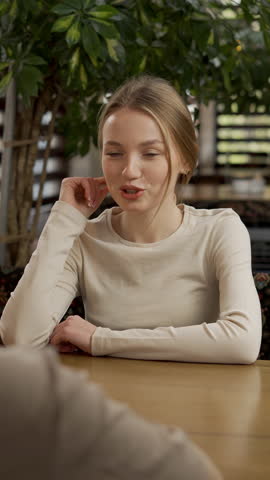 beautiful woman having meeting in cafe, looking at camera, speaking. Young woman has lunch at restaurant