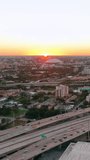Sunset horizon over Miami city, evening cityscape with road and car traffic. Drone flight over industrial landscape. Bright sun beams on horizon. Vertical video.