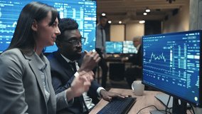 Two multi-ethnic brokers wearing formal clothes while working at computer in modern office. Professionals analysing financial or crypto charts and monitoring data on screen. Exchange trading. - Powered by Shutterstock - Get 15% off with code: PIKWIZARD15