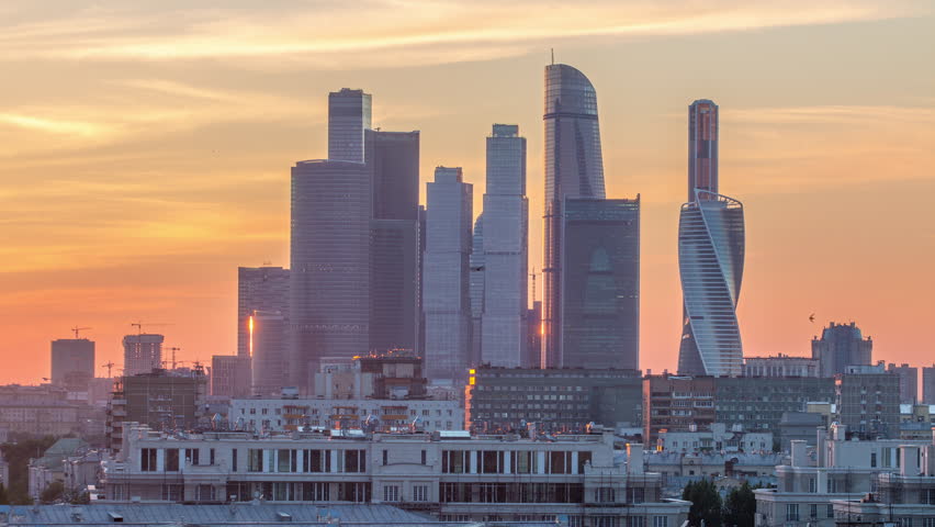 Moscow International Business Center and Moscow urban skyline after sunset day to night transition timelapse. Aerial view from rooftop. Close up. Colorful orange sky behind