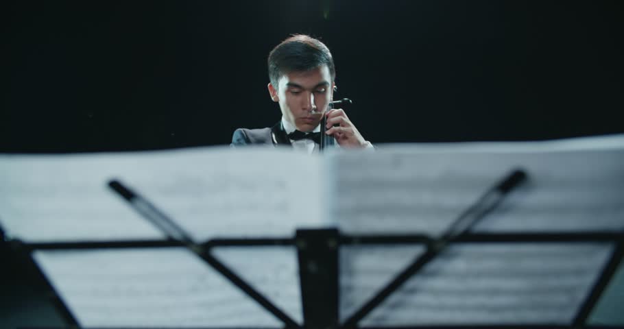 asian cellist male solo classical music performance, black background