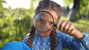 the girl holds magnifying glass in her hands. gaining knowledge and curiosity concept. a schoolgirl girl with a black lifestyle magnifying glass is examining something, park on the background - Powered by Shutterstock - Get 15% off with code: PIKWIZARD15