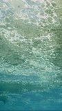 Vertical video, Close-up of oily fatty layer of garbage slowly drifts on water surface, Slow motion. View from underwater to thick layer of fat covering surface of Ocean on bright sunny day in sunrays