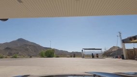First person view, FPV, from dashcam of car driving out of gas station in Tabernas desert, Almeria, Andalusia, Spain, Europe. Road trip video in POV in arid, dry climate	