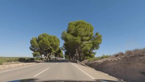 First person view, FPV, from dashcam of car driving on highway towards Valencia from Tabernas desert, Almeria, Andalusia, Spain, Europe. Road trip video in POV on beautiful tree-lined road with farms