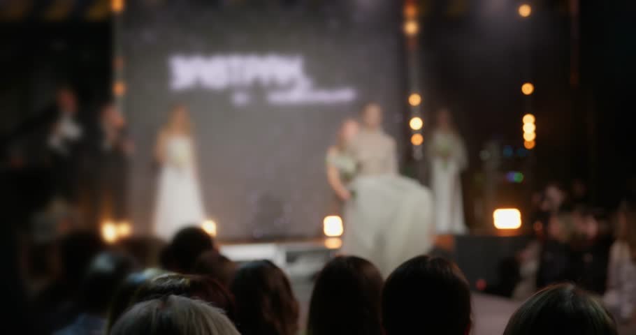 Fashion show at Fashion Week, female models walk down the catwalk between the audience showing a collection of new wedding dresses. A beautiful video for a screensaver on the theme of a fashion show Royalty-Free Stock Footage #3476141341