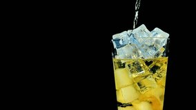 Golden Elixir: Inca Kola Soda Pouring into Glass of Ice in Slow Motion on Black Background in 4K Video
