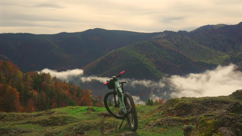 Electric bike stands on high mountain above clouds in autumn in Bavarian Alps. Brightly colored mountain e bike against German alps in higher than clouds. Theme travels in alpine by eletro cycle. 