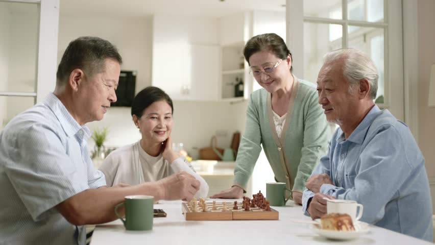 two senior asian men playing chess at home with wives watching by the side - Powered by Shutterstock - Get 15% off with code: PIKWIZARD15
