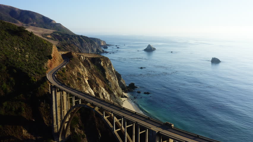 4k aerial footage of Bixby Creek Bridge on the Big Sur coast of California, USA. Ocean waves . Road to the San Francisco at sunset by a rocky coast. Stunning architectural in the natural landscape Royalty-Free Stock Footage #3476226011