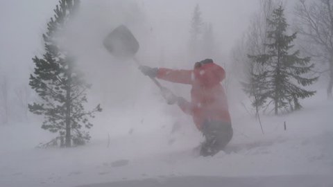 A man shoveling snow during a heavy storm in the Swedish mountains