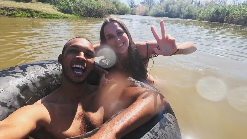 Selfie, swimming and couple in lake in nature live streaming on holiday, vacation and weekend. Peace sign, camping and man and woman on fun adventure for content creation, vlog and travel influencer