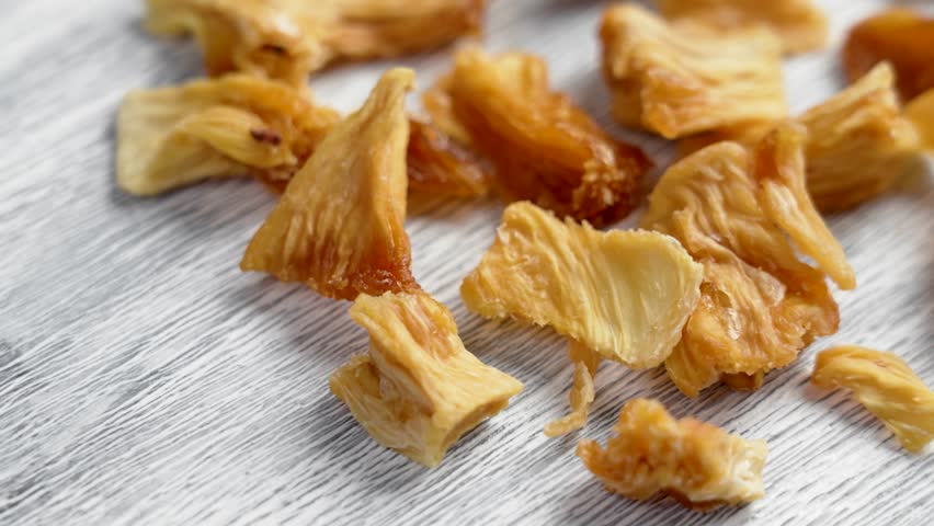 Sweet dried pineapple slices on a white textured board close up. Healthy fruity natural snacks. Rotation