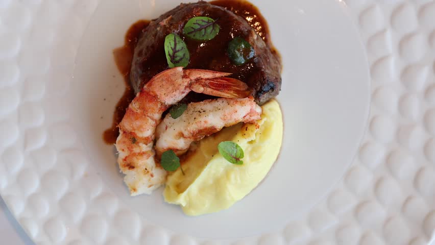 Surf and turf dish. 4K video with a surf and turf gourmet plate made from shrimps, beef tenderloin filet mignon steak and mashed potatoes.