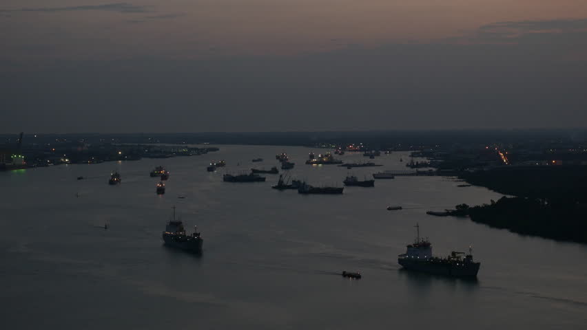 Aerial view of tugboat and Cargo transport ship passing industrial area in river. Twilight time.