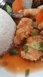 Close up of sweet and sour chicken fillet with rice and vegetables. Chinese food.
