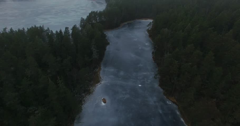 Flight over the woods of Tiveden National Park. Frozen lake and frosty trees. Tilting up revealing landscape.
