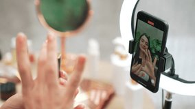 Rear view or behide camera screen display woman make natural beauty and cosmetic tutorial on natural garden video content. Beauty blogger showing how to beauty care to social medial audience. Blithe