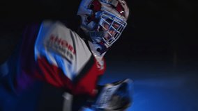 Close up Ice hockey goalie goaltender warms up before game Workout butterfly drill exercise. Goalkeeper stretches his legs at goal. Protective gear equipment. Blue light. Ice arena with lights off - Powered by Shutterstock - Get 15% off with code: PIKWIZARD15