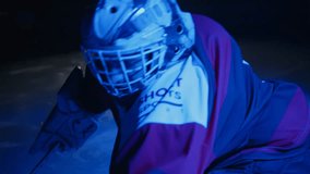 Ice hockey goalie goaltender warms up before game Butterfly drill exercise workout. Goalkeeper stretches his legs at goal. Protective gear equipment. Blue light. Ice arena with lights off - Powered by Shutterstock - Get 15% off with code: PIKWIZARD15