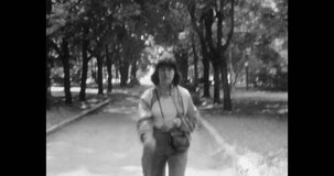 Beautiful young woman walking in summer park, close up. Cheerful brunette girl portrait smiling on city park background. Archival vintage black white film. Archive video. Old retro 1980s Moscow Russia