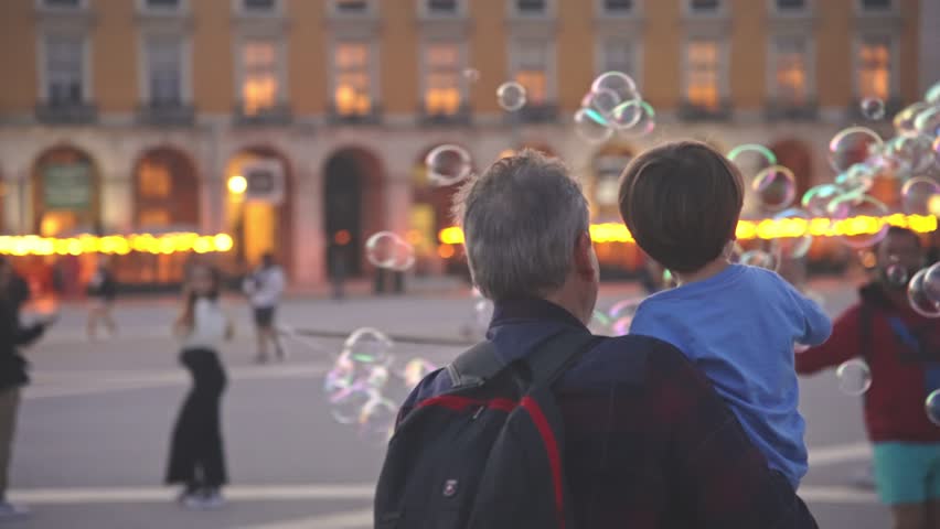 Happy childhood. Fun boy enjoy soap bubbles performance. Colorful fly show. Joyful child catch lot foam circles. Public place performer. Urban holiday square. Kid play city street. Entertainment event