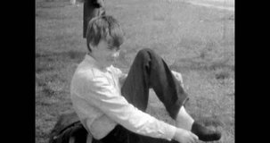 Boy taking off shoes, walking barefoot on grass. Nature unity. Young happy person relax in nature. active Carefree teenage. Archival vintage black white film. Old retro archive video. 1980s Crimea
