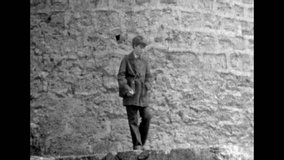 Teenager boy on medieval landmark backdrop. Historical site visit. Stone watchtower of defensive fort. Schoolboy on travel excursion. Archival vintage black white film. Old retro archive. 1980s Crimea