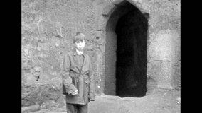 Boy walking through dark corridor of ancient medieval castle. Adventure expeditions travel. Mysterious passages in old stone building. Archival vintage black white film. Old retro archive 1980s Crimea