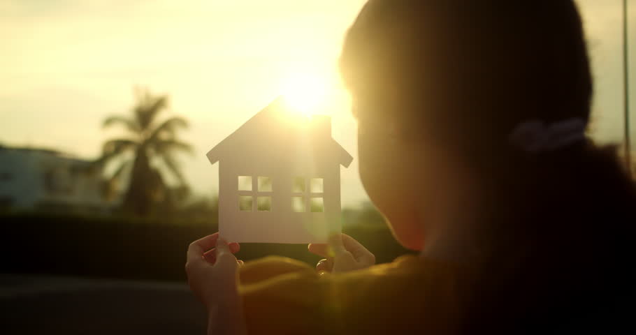 Child little girl male hands holding model of a paper house on sunset background. Concept of Happy Family Purchase Property, Home, Life, Insurance, Care, Savings, Mortgage, Estate. Symbol happiness