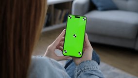 Woman using smartphone vertical green screen. Female holding in hand portable gadget. Tracking markers. Indoors. Browsing social network, news. Mock-up for tracking. Watching content video blog 4K