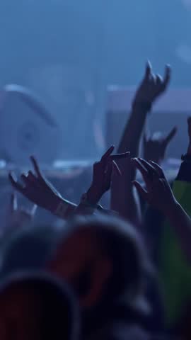 Fans at rock concert. People raising and claping their hands in stage lights. Unrecognizable fans dancing at a concert or festival party. Silhouettes of concert crowd , Vertical Screen