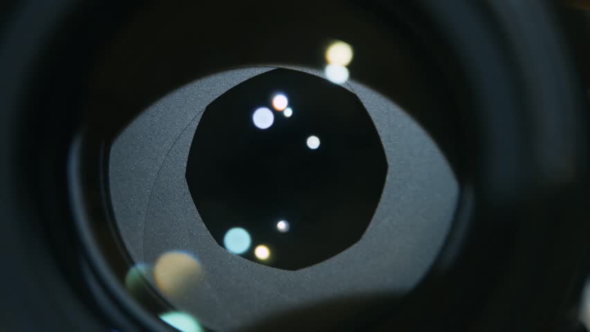Camera prime lens. Close Up of closing professional camera aperture, with lights around. Big Digital Eye