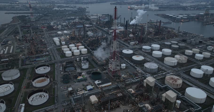 Refineries and the three steam crackers in the port of Antwerp, Belgium at dusk. Petrochemical silos and storage containers. Chemical production, oil and chemical production. Aerial drone view.