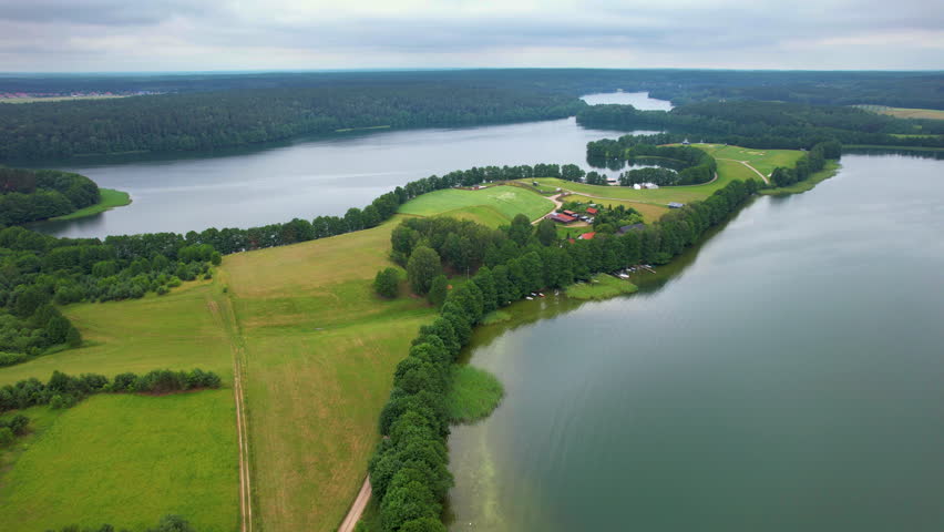 Beautiful Lake With Houses on Shore. Pond is Calm and Peaceful. Majestic Aerial View of Calm Lake With Islands in Poland. Village Houses on Shore of Paradise Lake. Peaceful Reflected on Water. 