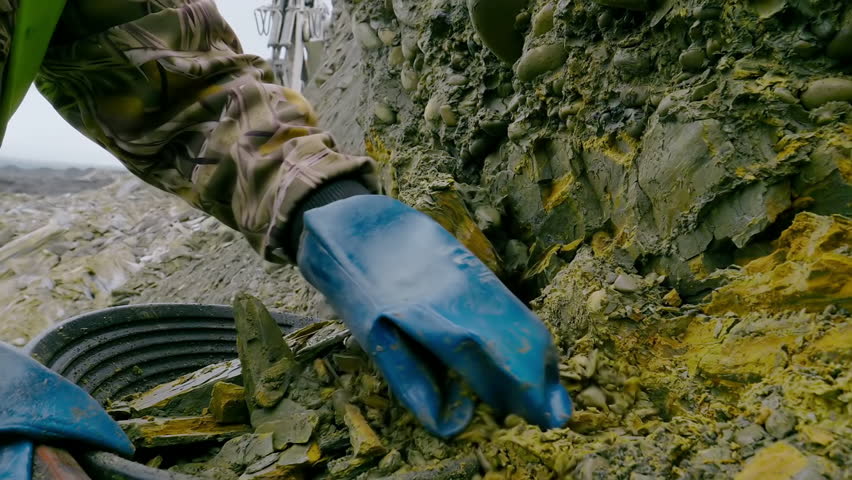 Close-up of a worker dealing with rock mining at the huge industrial quarry. A Worker is mining the rocks in search of precious metals. A Worker is mining the material from the natural rock formation