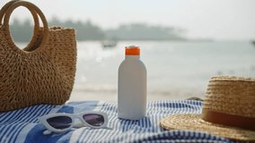 Beach essentials placed on striped towel, white sunscreen bottle, stylish sunglasses, straw hat, woven tote. Summer vacation items on sandy shore, sea backdrop. Holiday trip, skin care in sunlight. - Powered by Shutterstock - Get 15% off with code: PIKWIZARD15