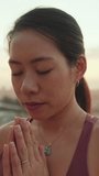 VERTICAL VIDEO: Close-up, girl meditating while sitting on viewing platform at dawn