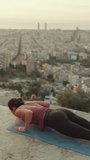 VERTICAL VIDEO: Young woman practices yoga at sunrise on viewing platform. Girl in snake pose