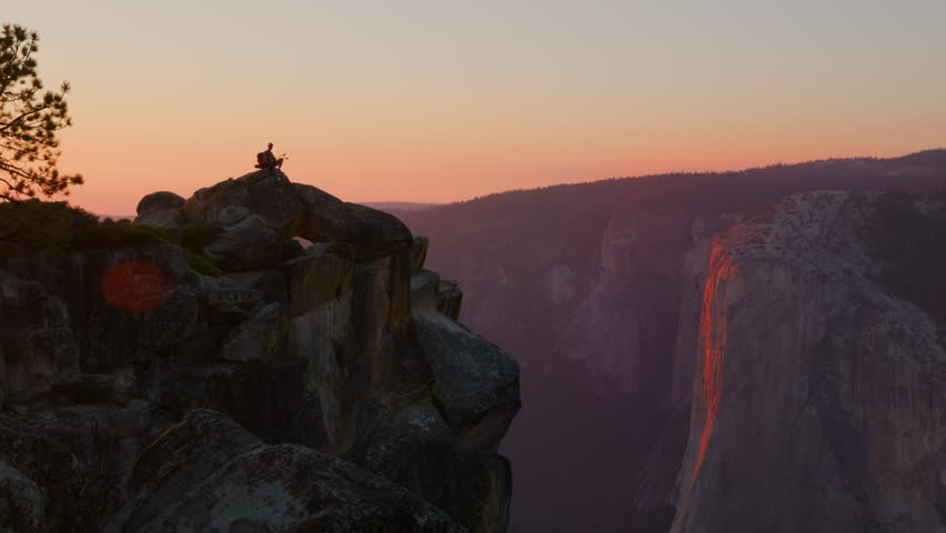 Fantastic view of majestic rock formations of famous Half Dome, lonely man admiring the beauty of impressive ancient rocks on the peak under orange skies. High quality 4k footage Royalty-Free Stock Footage #3476857891