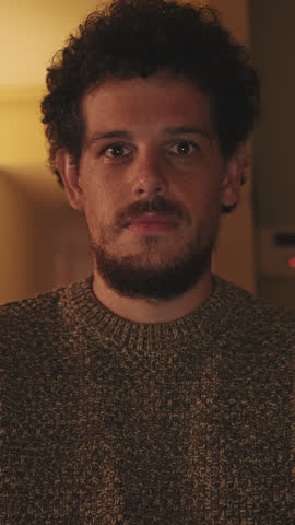 Vertical video, Guy is talking on video chat on laptop while sitting in the kitchen in the evening