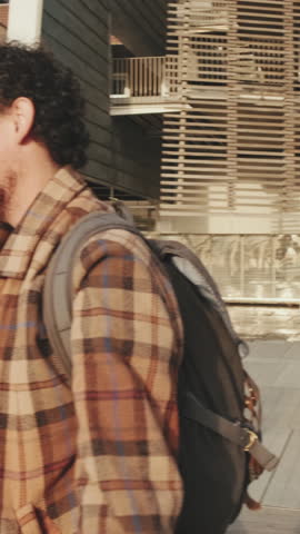 VERTICAL VIDEO, Students greet classmates outside. Young people joyfully greet friends on the street next to the university building