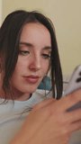VERTICAL VIDEO, Close-up of young woman using phone while sitting on sofa at home